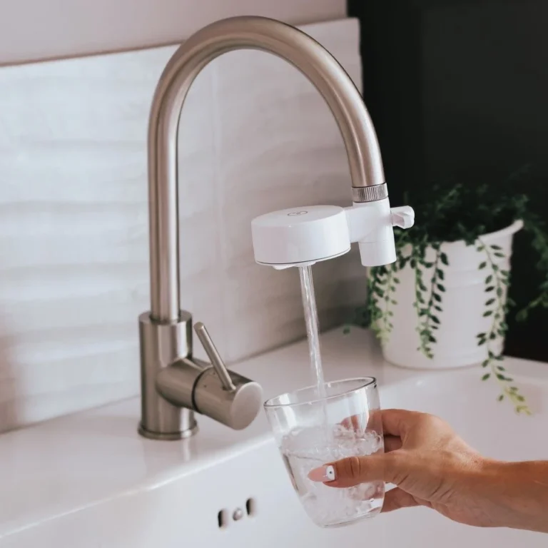 Filtro de grifo instalado y un vaso sirviendo agua